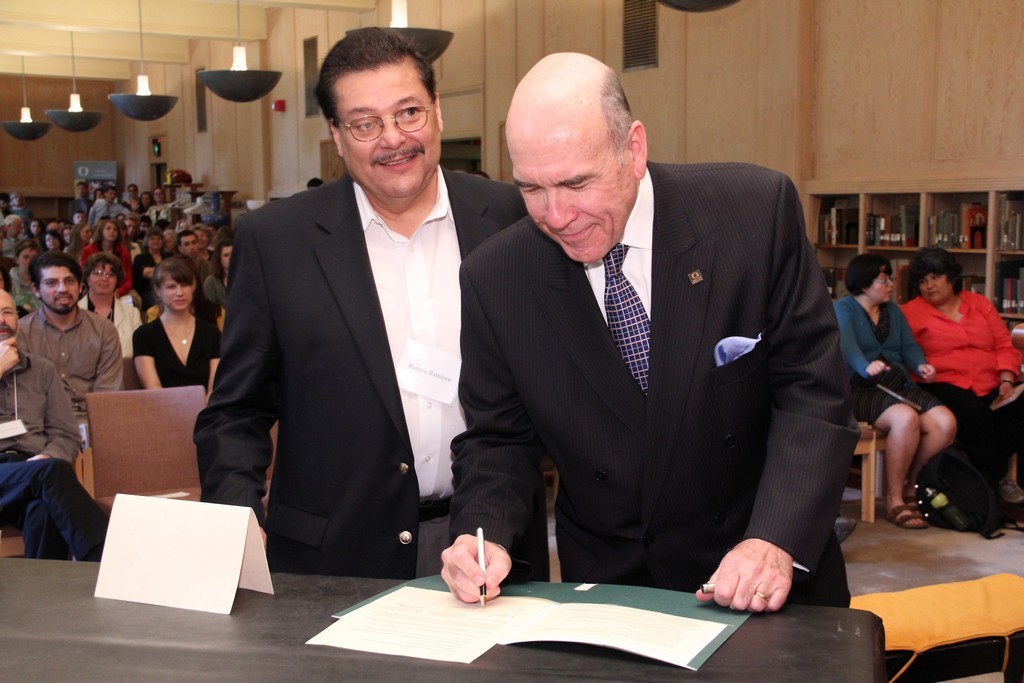 June 6, 2011—UO President Richard Lariviere (right) and PCUN President Ramón Ramírez sign documents marking the transfer of historic papers of Pineros y Campesinos Unidos del Noroeste to the UO Libraries’ Special Collections and University Archives / photograph by Jack Liu.